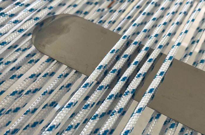 Precision is key during the wefting stage of D.I.Y. outdoor chair weaving – use a steel rule or palette knife to weave the rope neatly for a professional finish.
