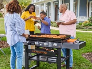 Family standing around Blackstone griddle cooking