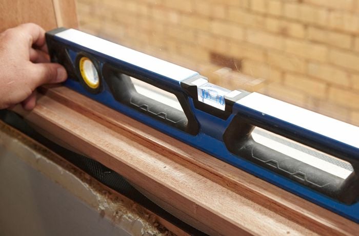 Using a spirit level to check the window is level.