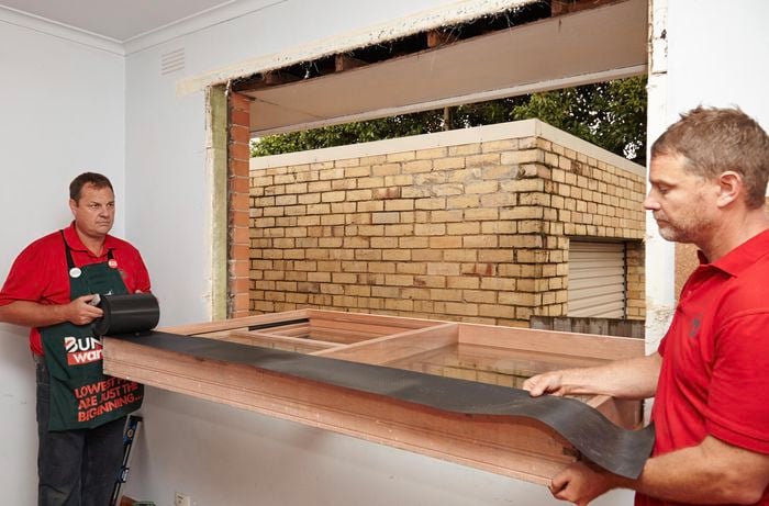 Bunnings team members installing waterproof flashing onto the bottom of the sash window frame