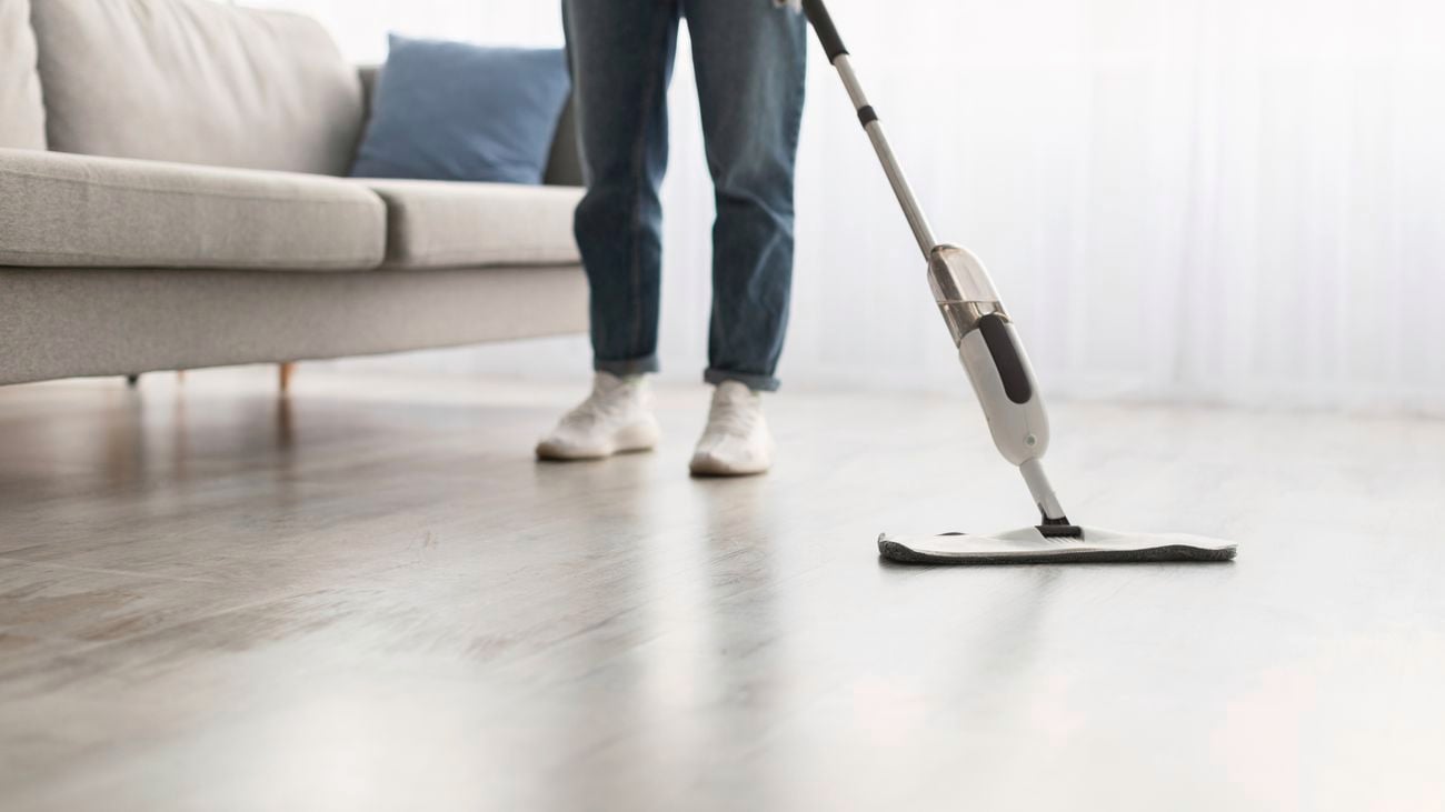Woman washing hardwood laminate flooring using water spray mop pad