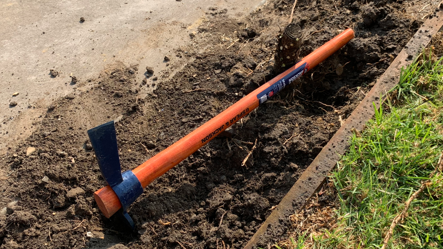 Mattock with one blade buried in the ground