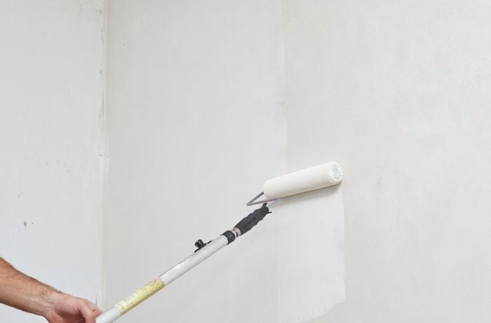 White paint being applied to a wall with a paint roller