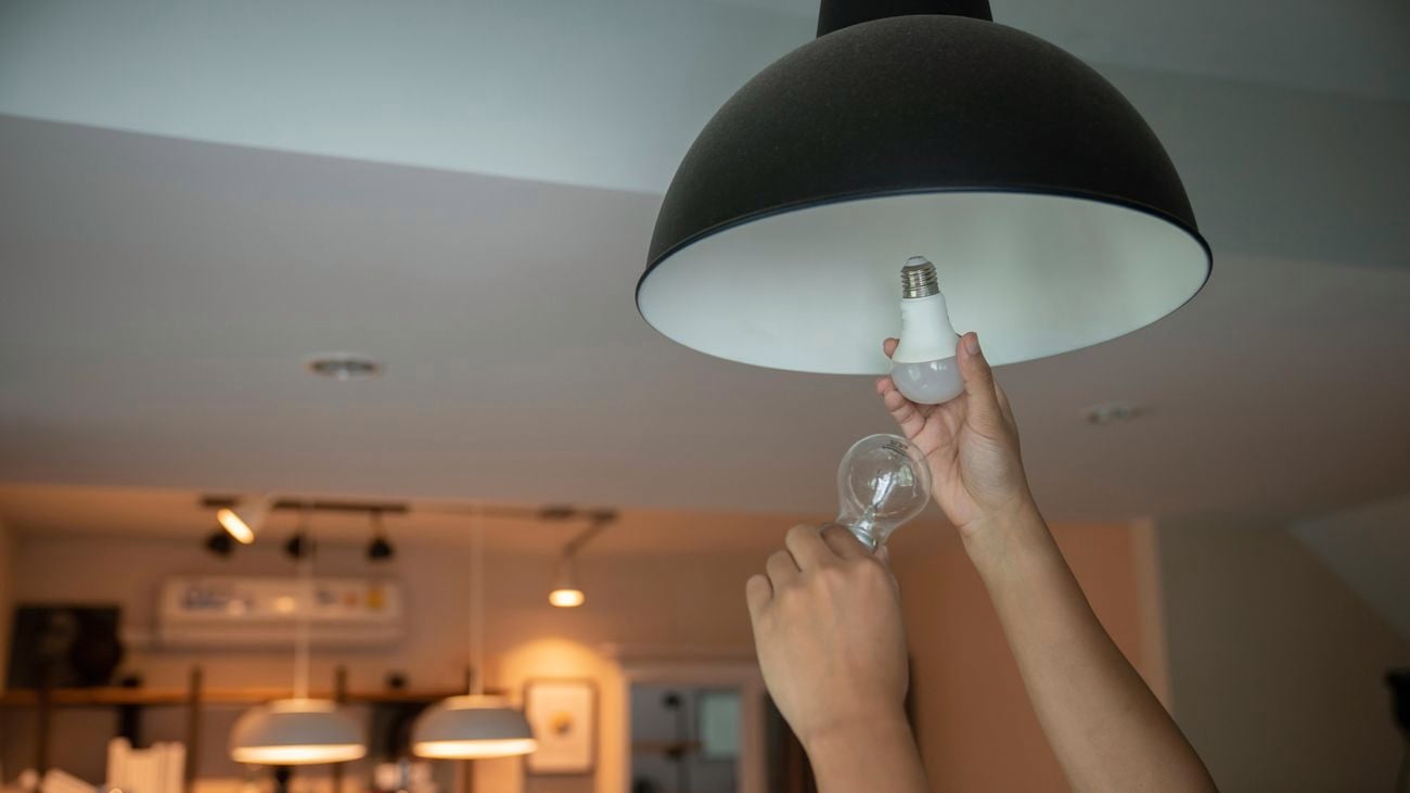 Hands changing light bulbs with new LED light bulb.