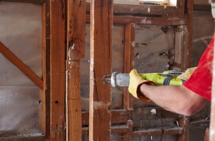 A vertical stud being cut in half with a saw, next to a stud already cut in half