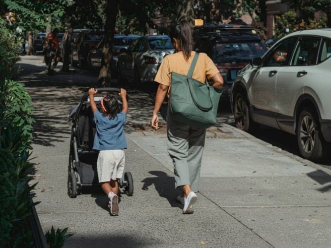 lady and child walking down the street, the boy is pushing a stroller