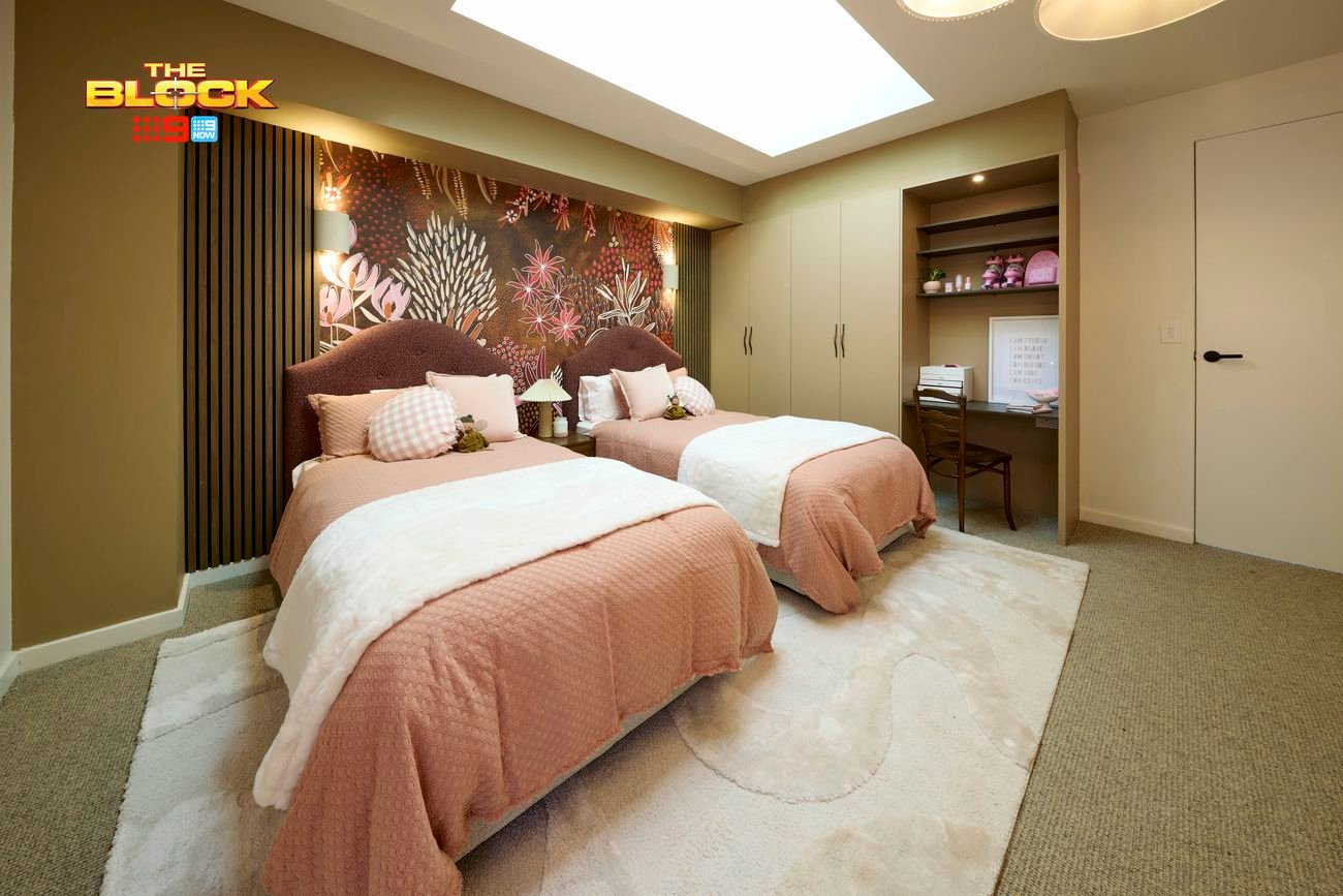Olive bedroom with twin beds featuring blush linen and deep blush bucle bead heads backing onto floral wallpaper. Also showcasing a wardrobe and desk on the side.,