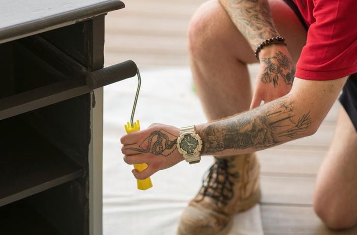 Applying a coat of paint with a paint roller.