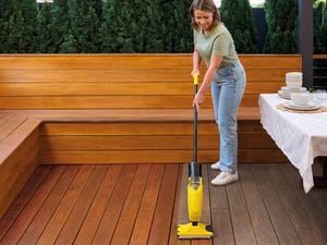 A woman applying Cabot’s Easy Deck onto timber decking