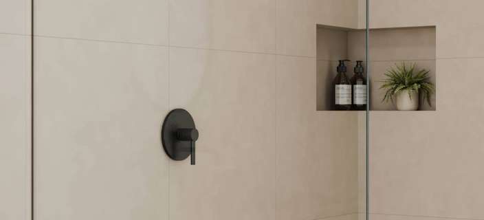 Minimalist bathroom shower scene featuring a glass shower enclosure and neutral-toned finishes.