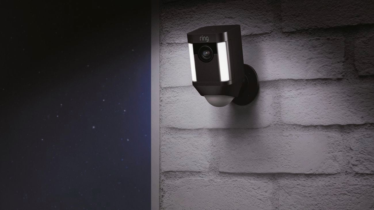 An outdoor spotlight camera hung on a brick wall