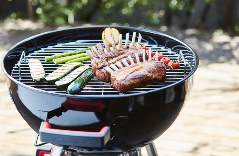 Rack of ribs and vegetables cooking on kettle barbecue
