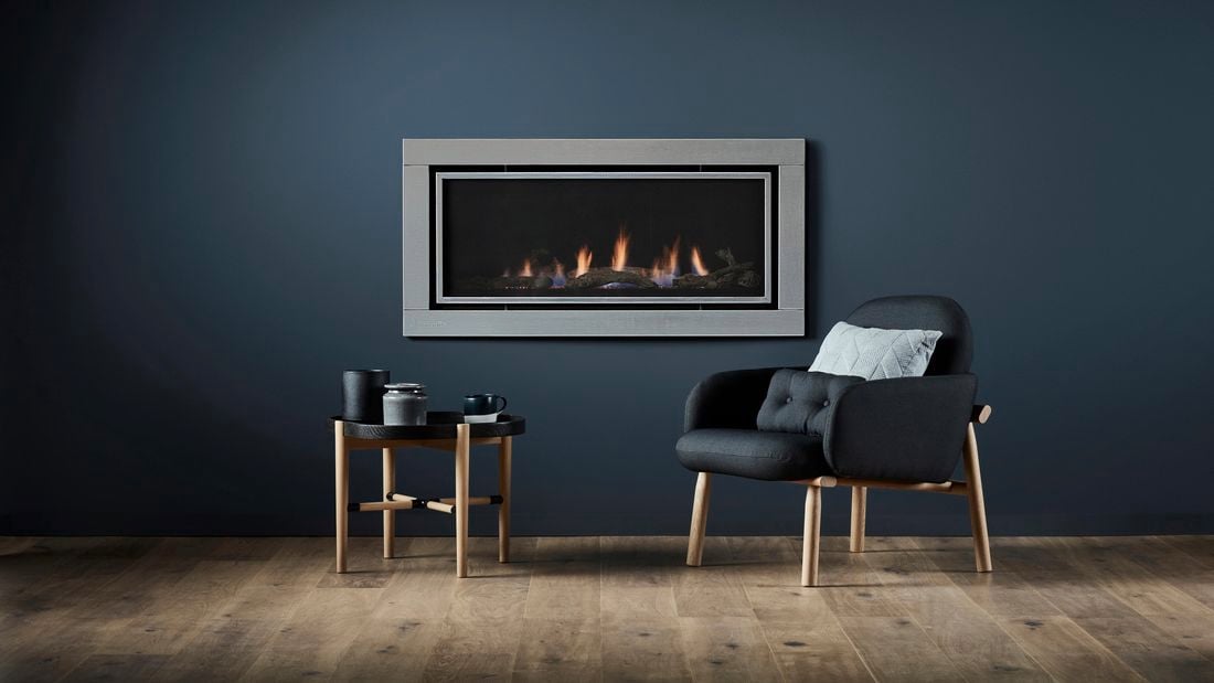 Gas fireplace inset into the wall with a chair and side table.