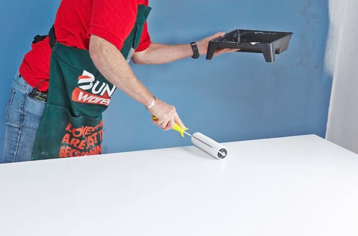 Person painting door with paint roller.