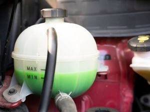 Car coolant reservoir is filled with green coolant