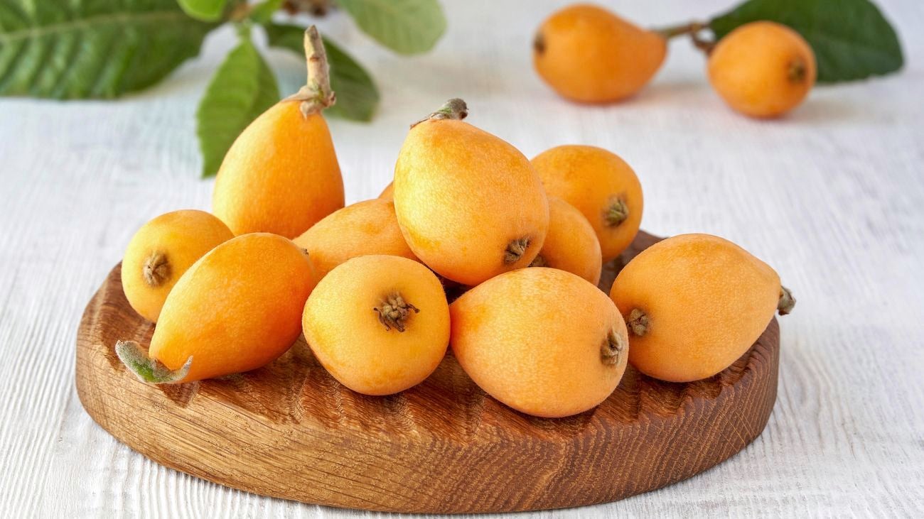 Orange loquat fruit on a wooden board
