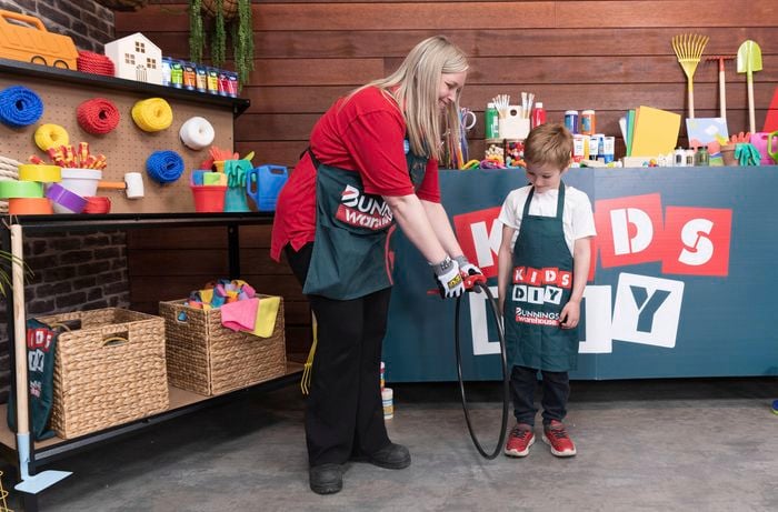 A Bunnings Team Member is helping a boy with a hula hoop DIY project. 