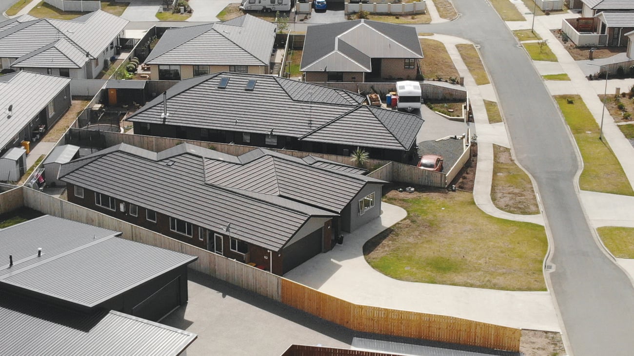 Aerial shot of a completed home, with garage, driveway and dark wooden panel walls