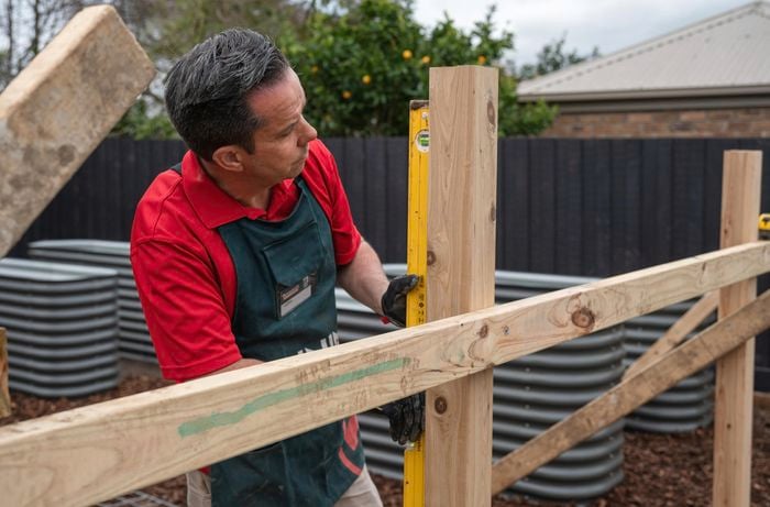 A Bunnings Team Member holding a Spirit level against a Timber post