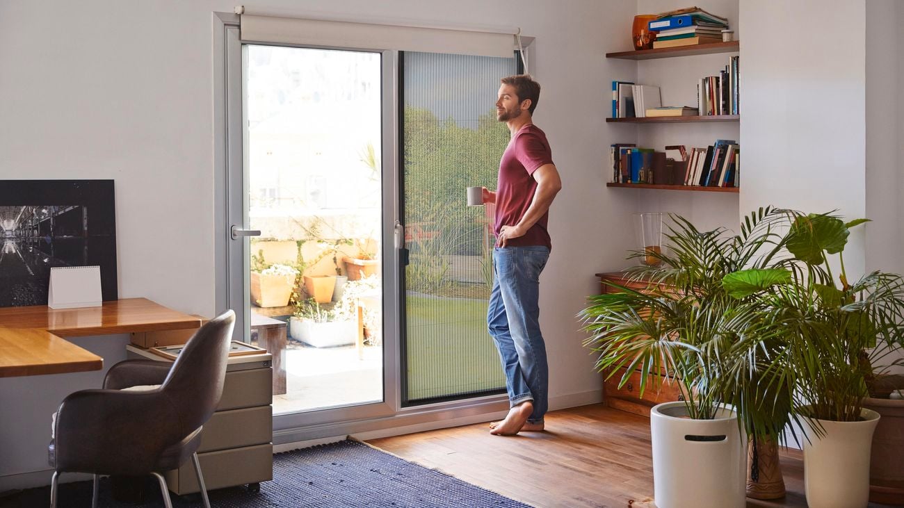 A man stands in front of a black aluminium framed Pillar flyscreen door