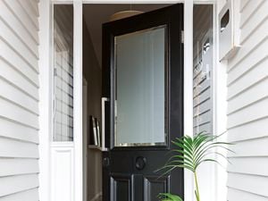 Black front entry door of a home featuring a frosted glass panel and a smart door lock.