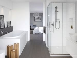 A white bathroom with dark grey slate floor opening off a bedroom