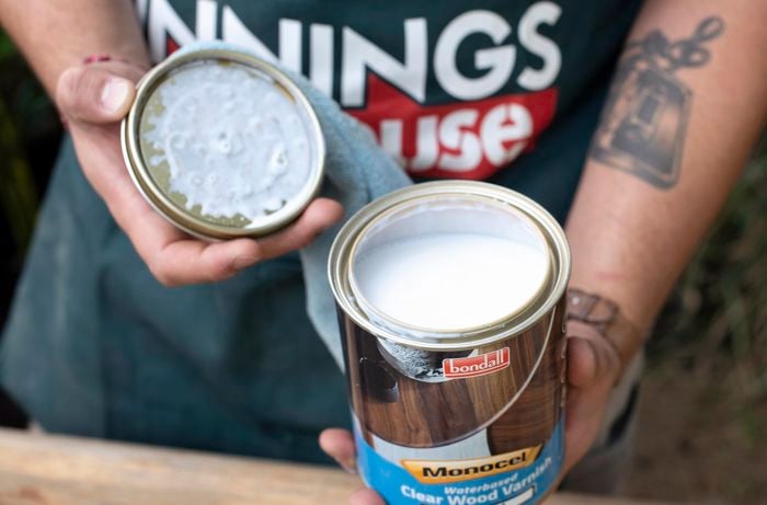 Person holding open can of white paint in hands.