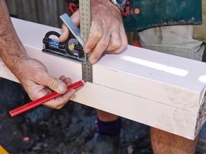 Person marking a post using a set square and pencil