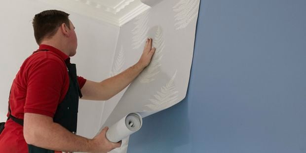Bunnings team member hanging a sheet of wallpaper.
