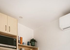 Kitchen with a wooden table and chairs and a split system air conditioner on the wall.