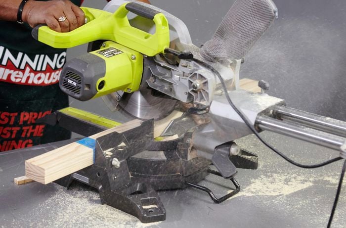 A person cutting pine timber with a drop saw
