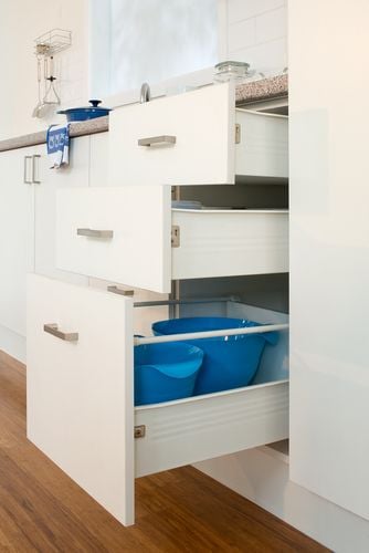 Three kitchen drawers holding bowls and other utensils