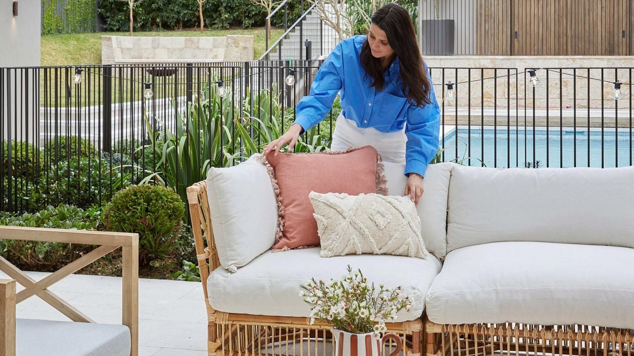 Person adjusting cushions on an outdoor lounge setting