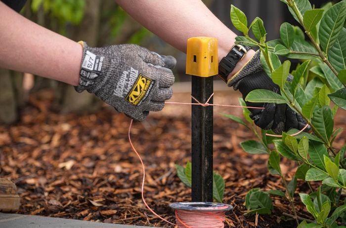 person tying string to a small metal post
