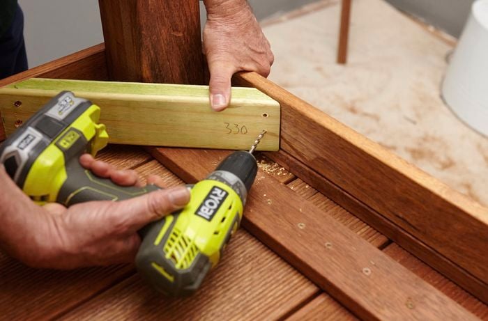 Person drilling pieces of wooden table together.