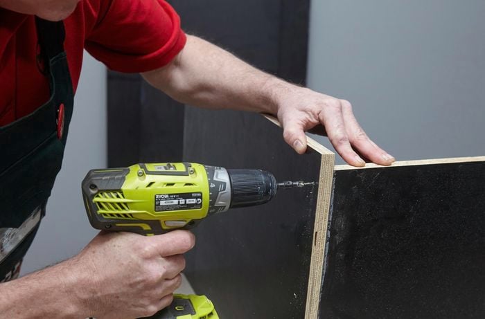 Person drilling two pieces of ply
