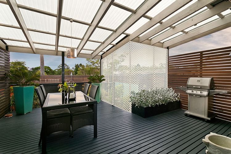 Covered outdoor timber decking area with dining table and decorative screens