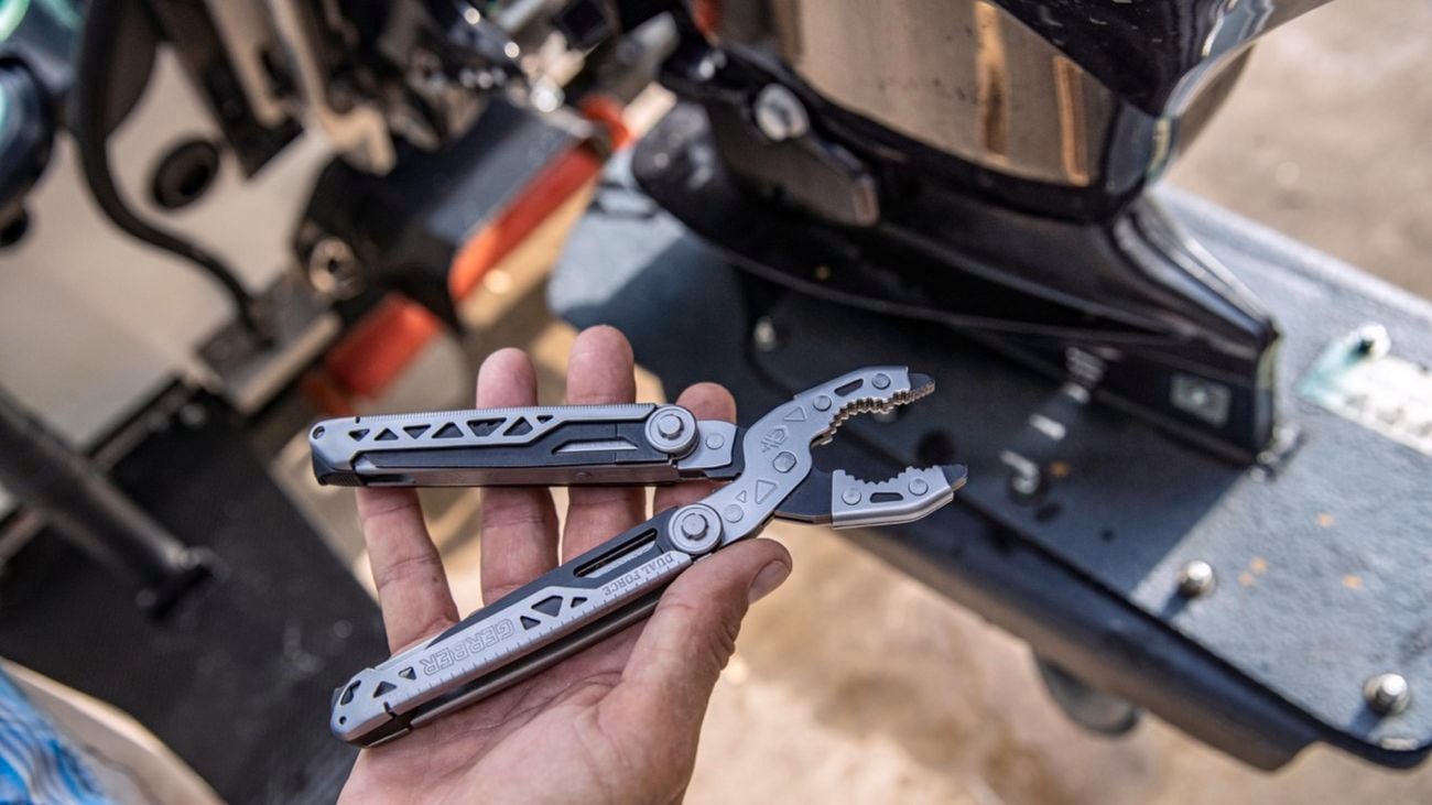 a Gerber Dual-Force lying on a face-up palm, with a workshop blurred in the background.