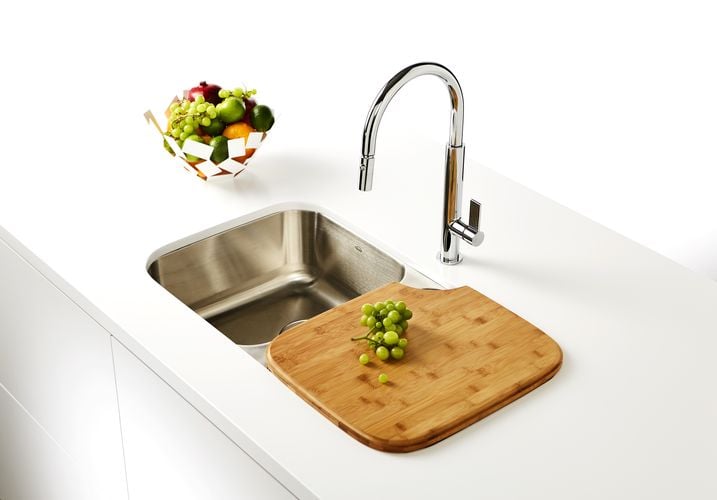 Kitchen benchtop with stainless steel sink, chopping board with grapes, and fruit bowl