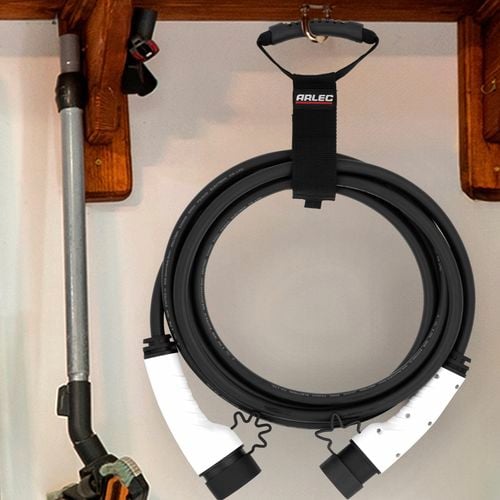A black Arlec cable holder mounted on a wall, neatly holding a coiled black cable with white connectors at each end, organized in a garage setting.