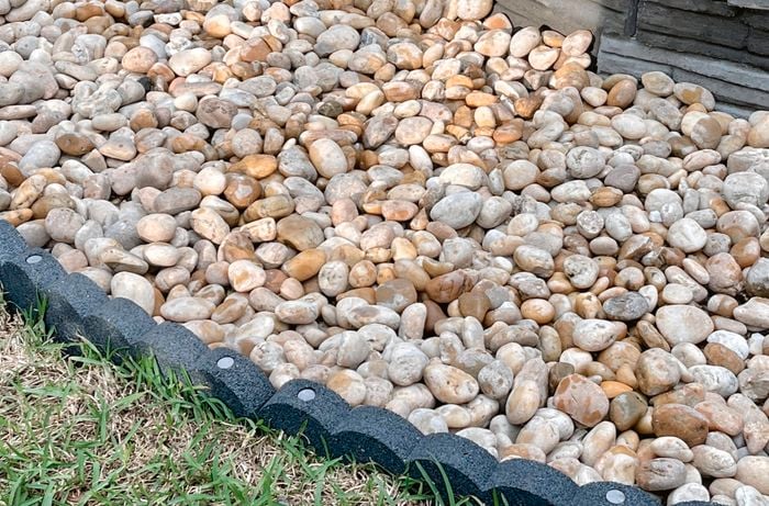 Large pebbles fill a fire pit space within flexible garden edging