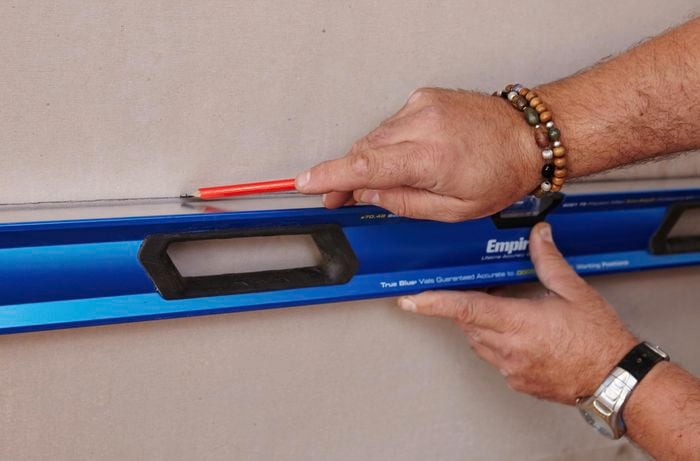 A spirit level being used to mark a straight line on a wall