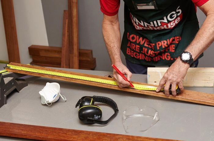 Person using measuring tape and making a mark on piece of timber.