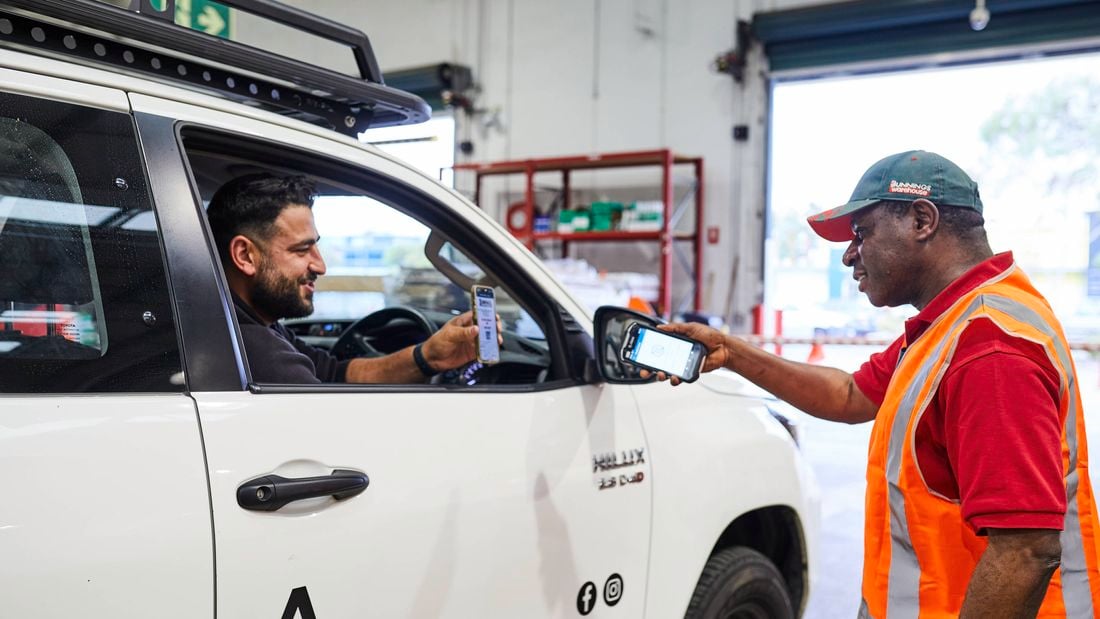 A tradie in a ute shows his purchases through the PowerPass app to a Bunnings Warehouse team member