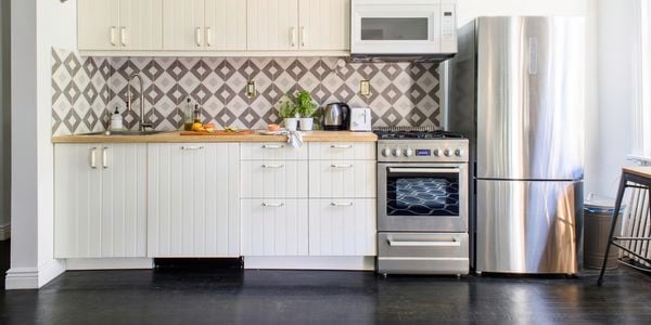 White kitchen with stainless steel appliances and overhead air conditioning unit