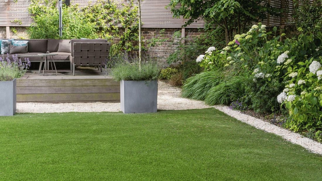 A garden with lush green grass and raised entertaining area