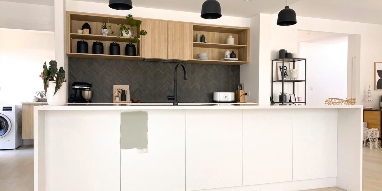 Modern kitchen with a white island bench in it and wooden cupboards.