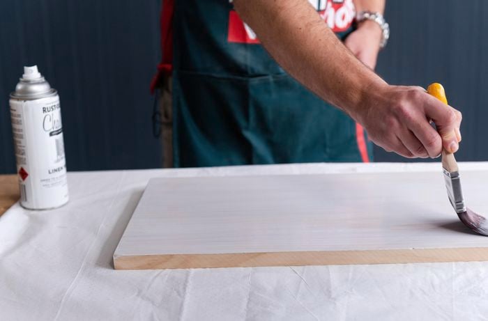 Bunnings team member painting the timber with a paint brush
