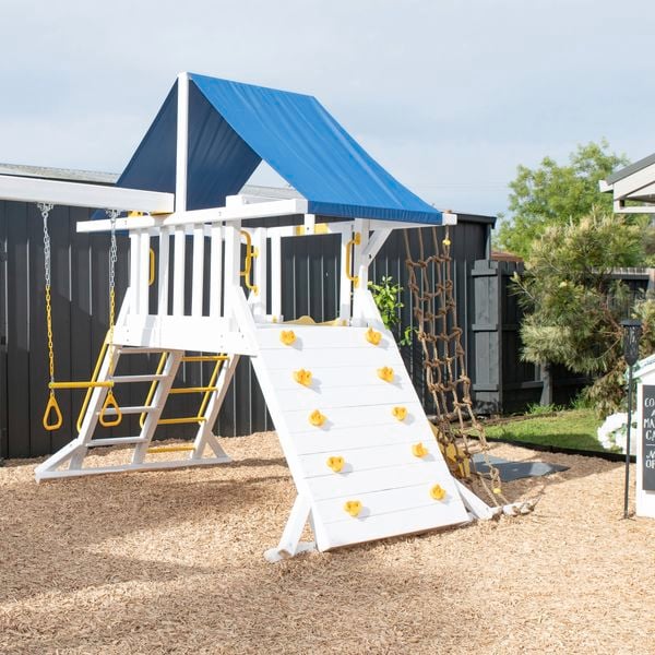 After image of a bright white kids adventure play set with swings, climbing apparatus with a blue shaded rooftop.