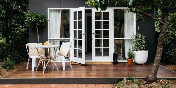 Granny flat with wooden porch with outdoor table/chairs set and plants